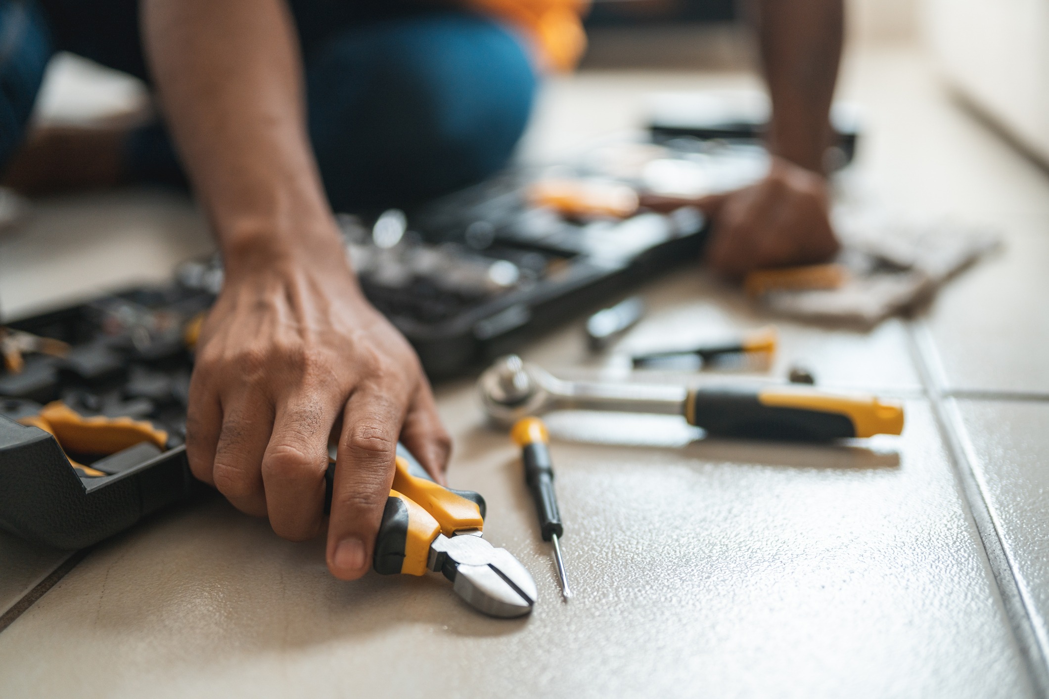 A plumber pulls tools out of his toolbox to work on a leak in a bathroom.